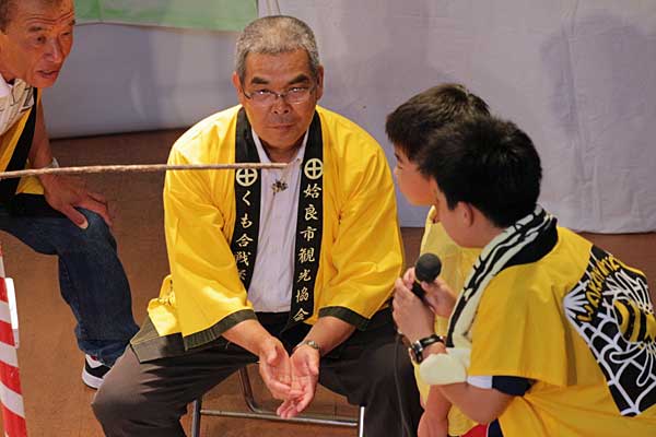 加治木町くも合戦保存会の吉村会長とビオトープ孟子の江川さん、司会の中学生